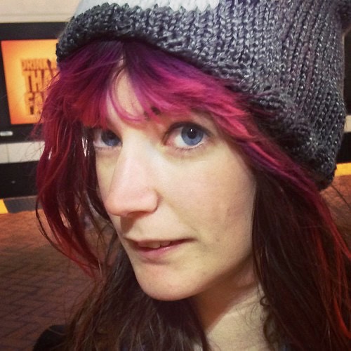 a woman with red hair wearing a knit hat