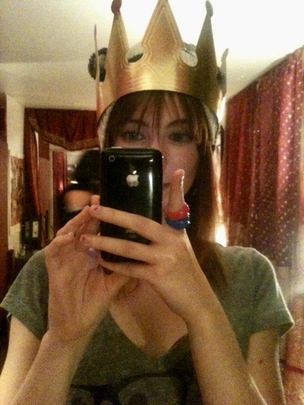 a woman taking a picture of herself wearing a crown