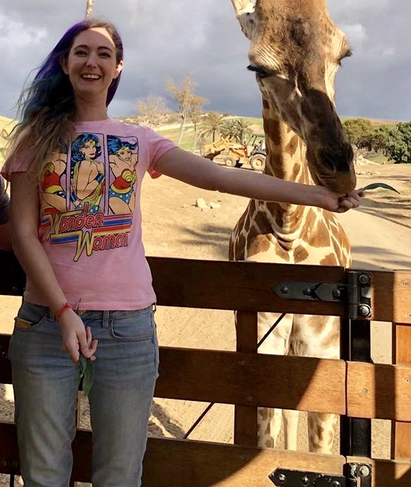 a woman standing next to a giraffe