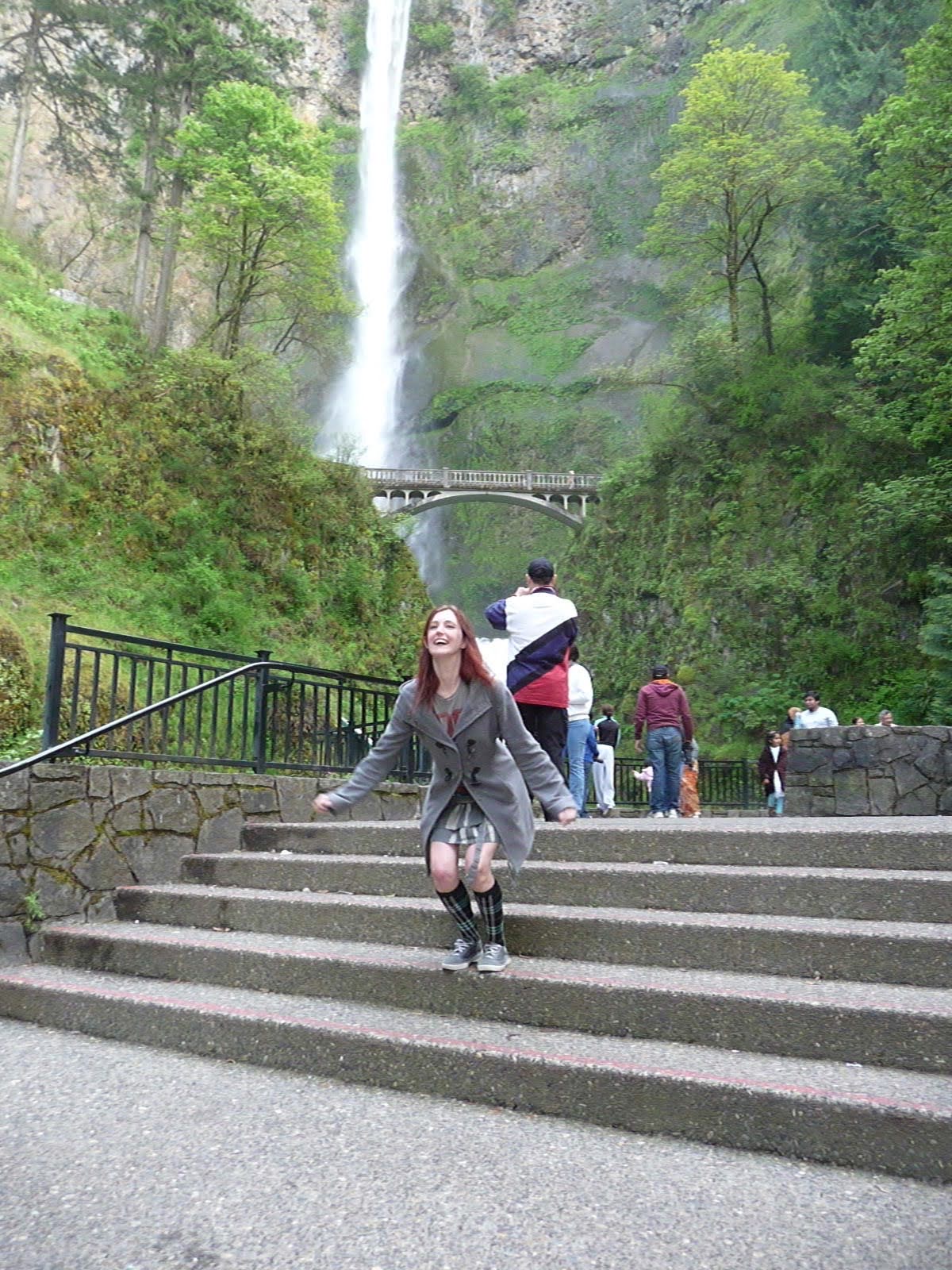 a woman is walking up some stairs in front of a waterfall