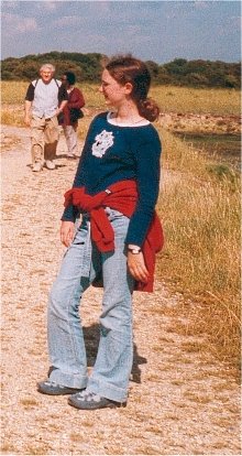 a woman is walking down a dirt road