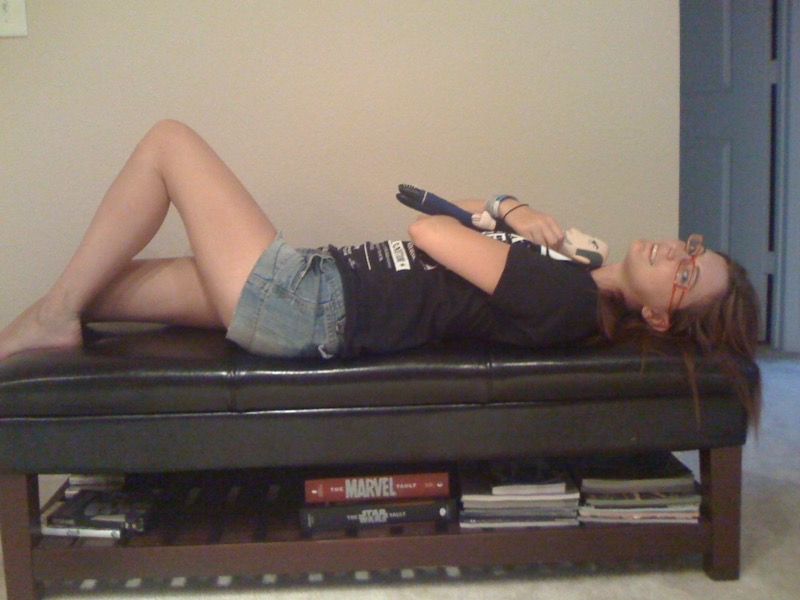 a woman laying on a couch with a remote control