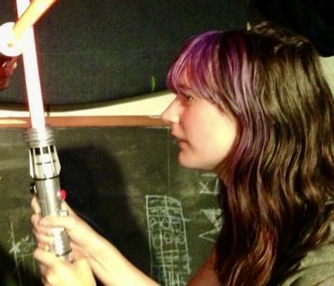 a woman holding a microphone in front of a blackboard