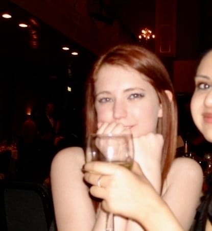 two women are sitting at a table with wine glasses