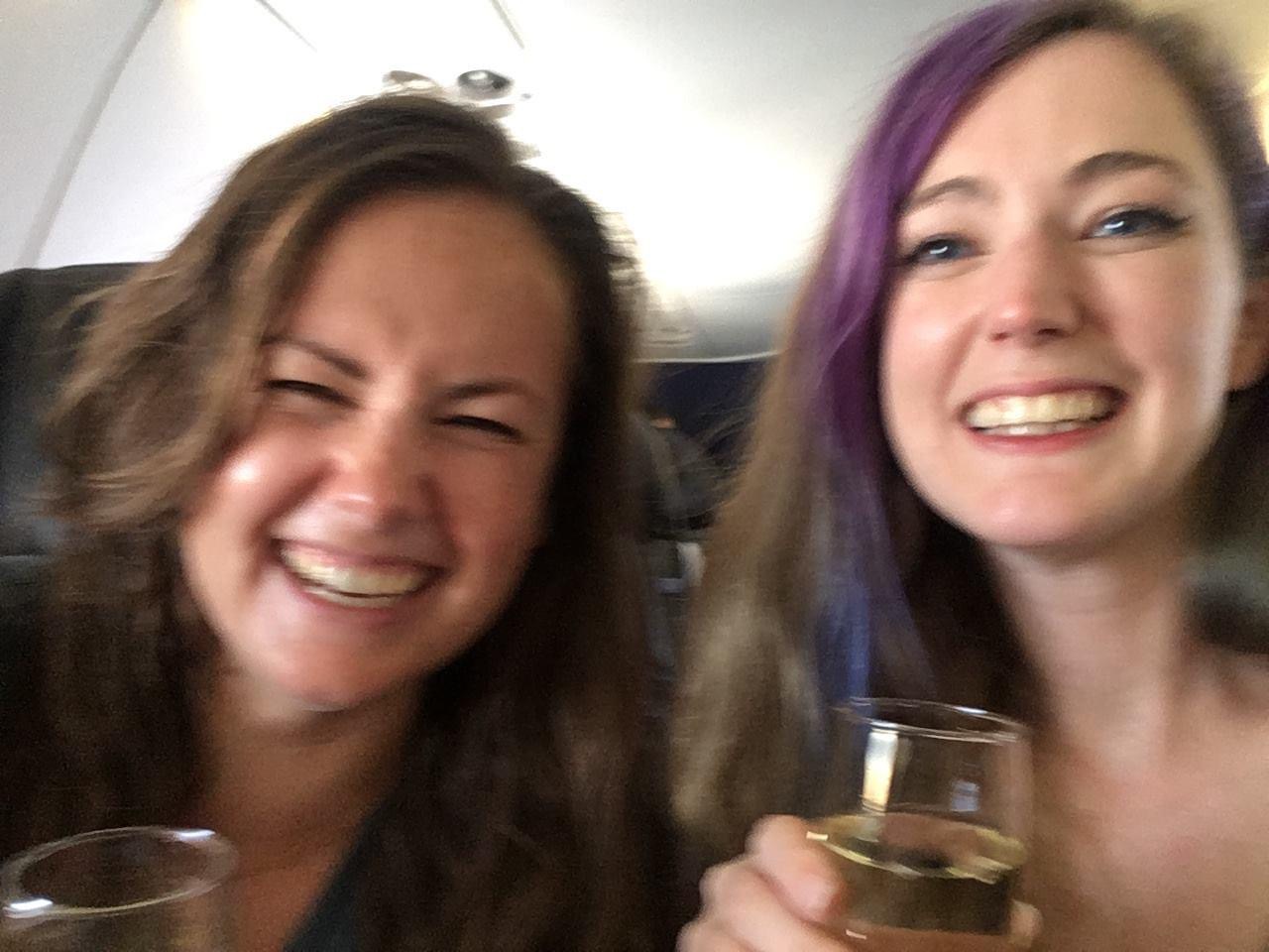 two women are smiling and holding wine glasses