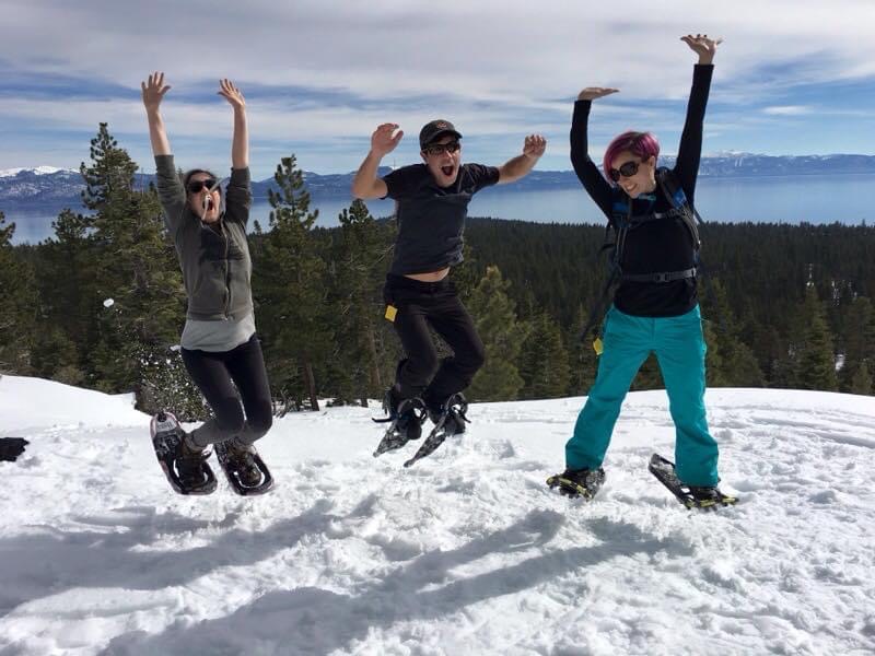 two people jumping in the air on a snowy mountain