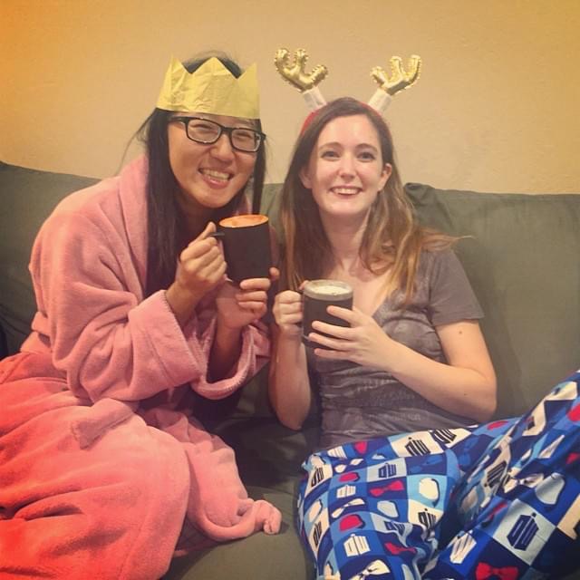 two girls sitting on a couch with their hands in their mouths