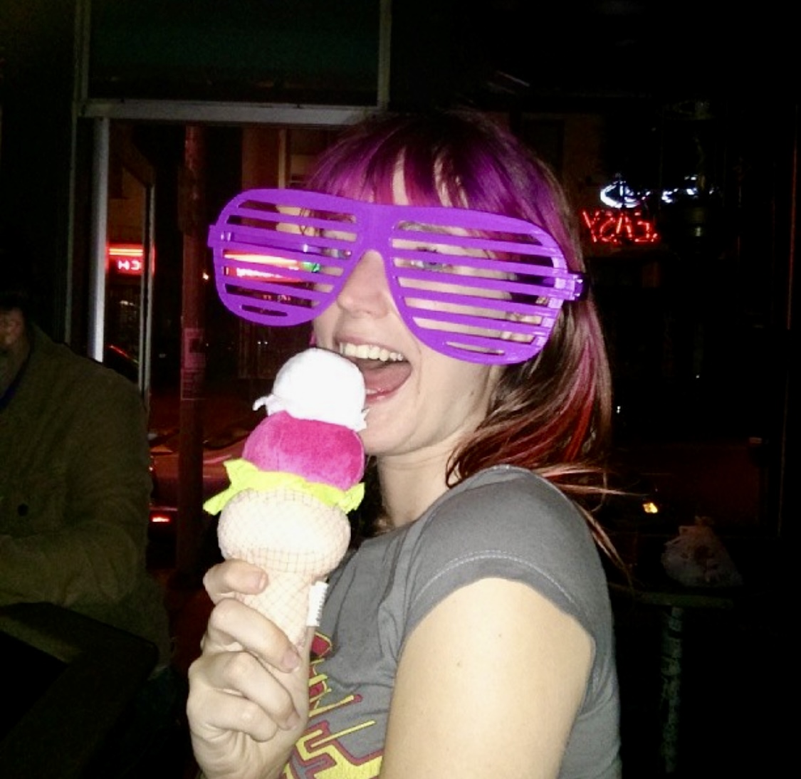 a woman with pink hair and sunglasses eating an ice cream