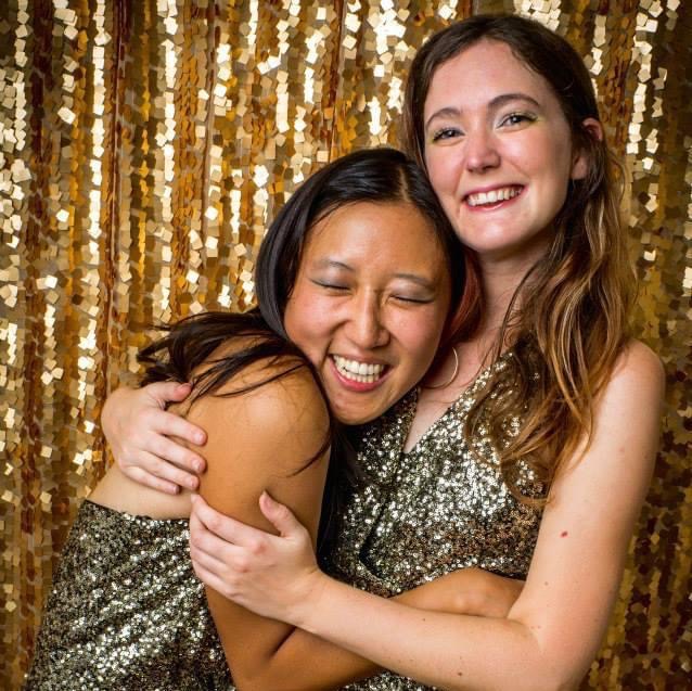 two women hugging in front of a gold sequin