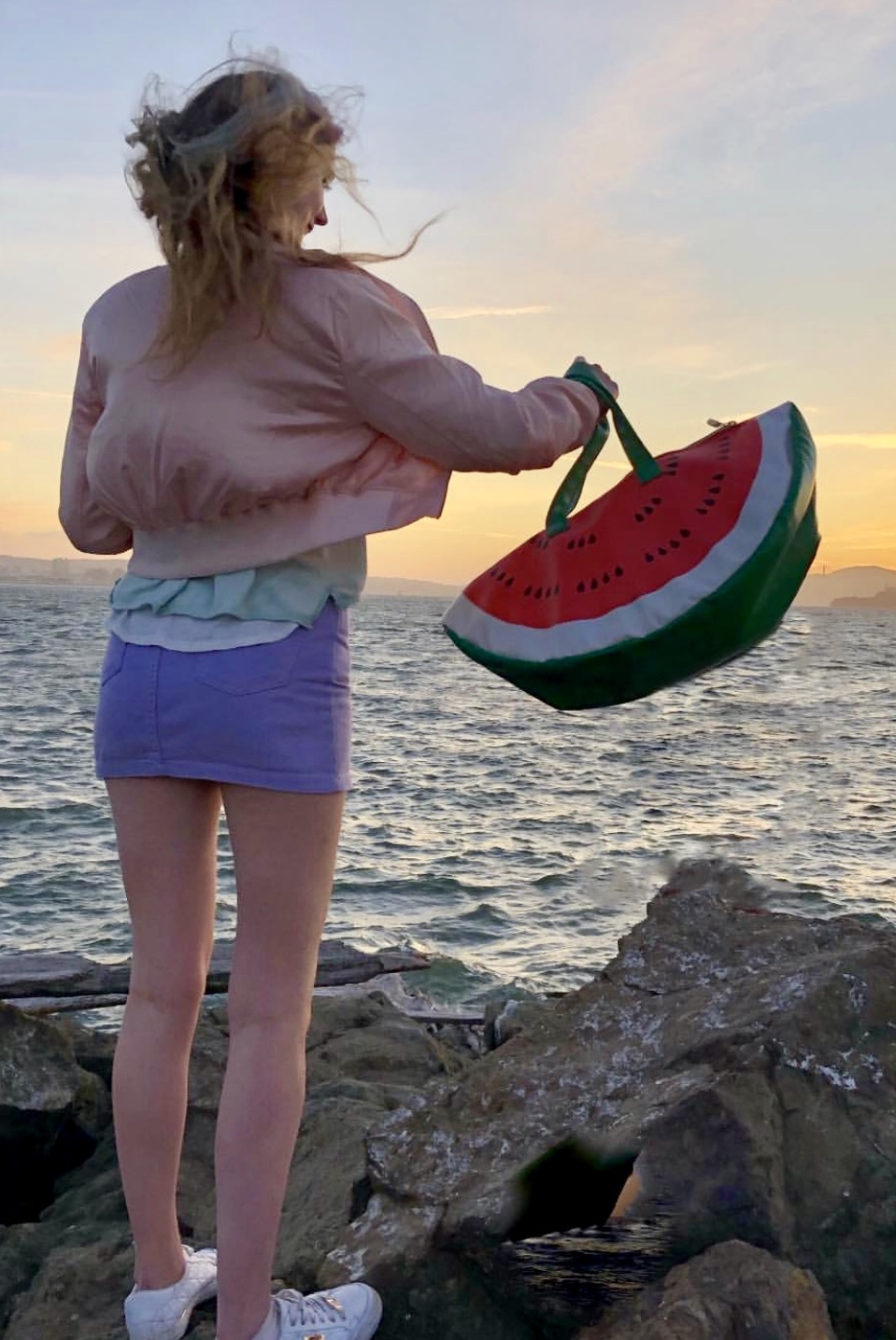 a woman standing on rocks near the watermelon