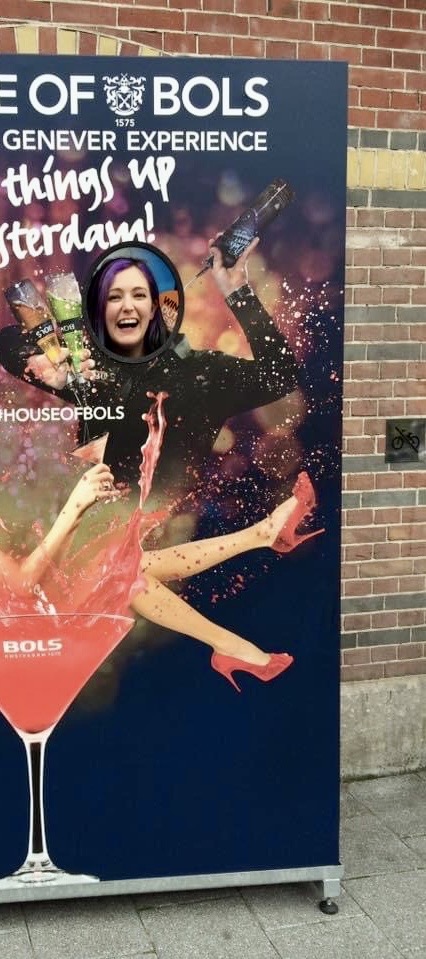 a woman in a black dress is standing next to a large poster OF ®BOLS
GENGER EXPERIENCE

~