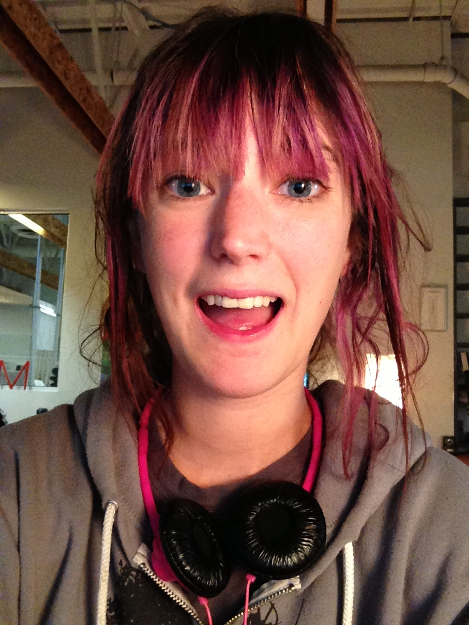 a woman with pink hair and a grey hoodie