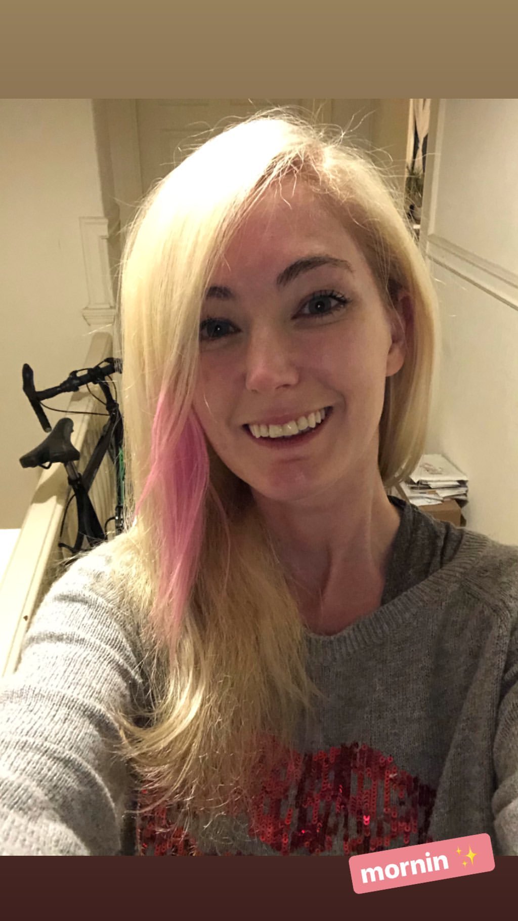 a woman with pink hair and a grey sweater