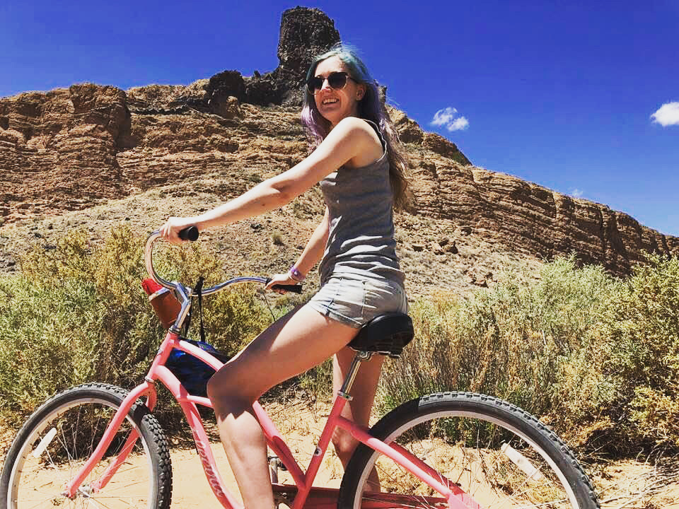 a woman riding a bike on a dirt road