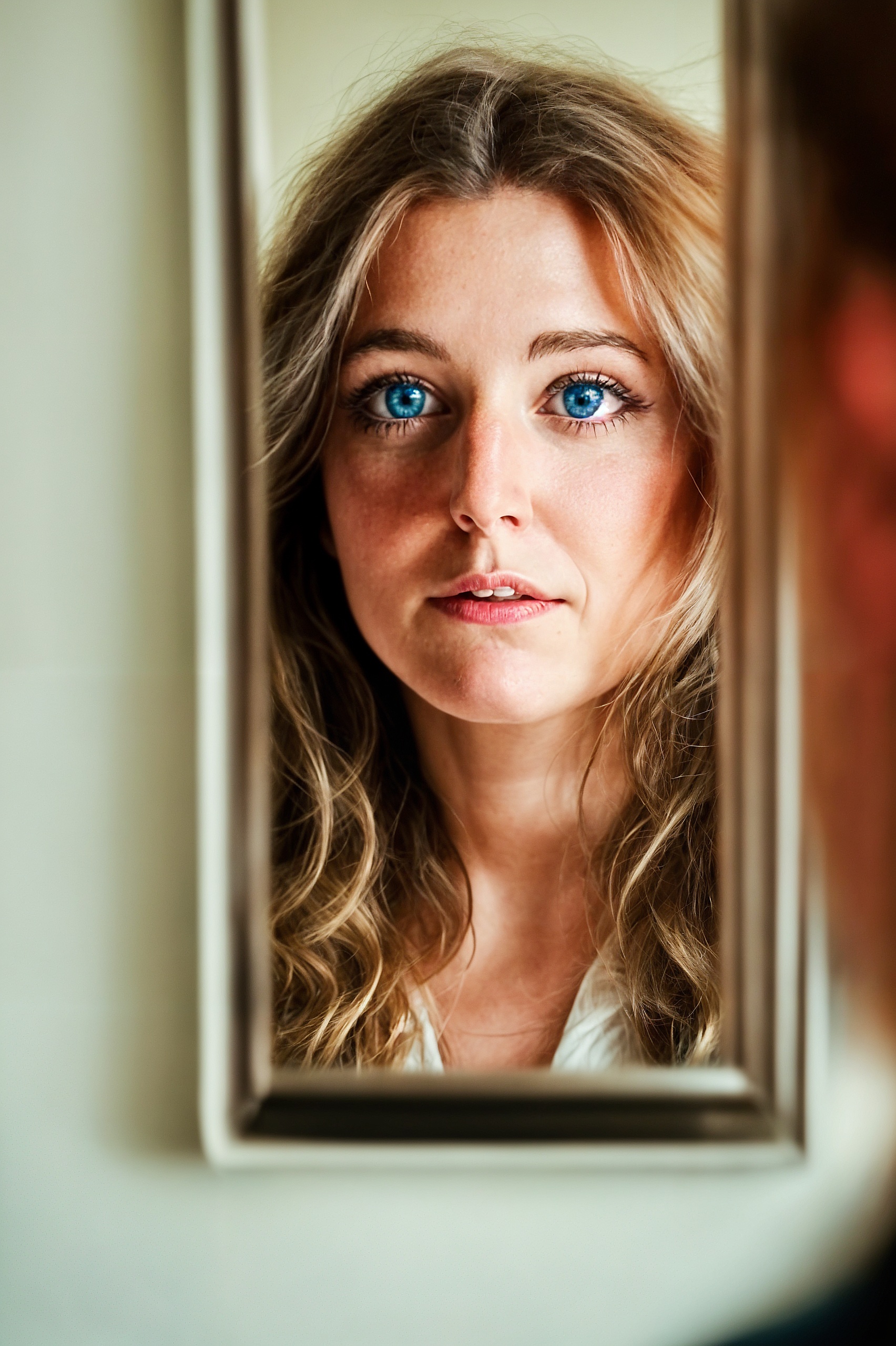 a woman with blue eyes looking in a mirror