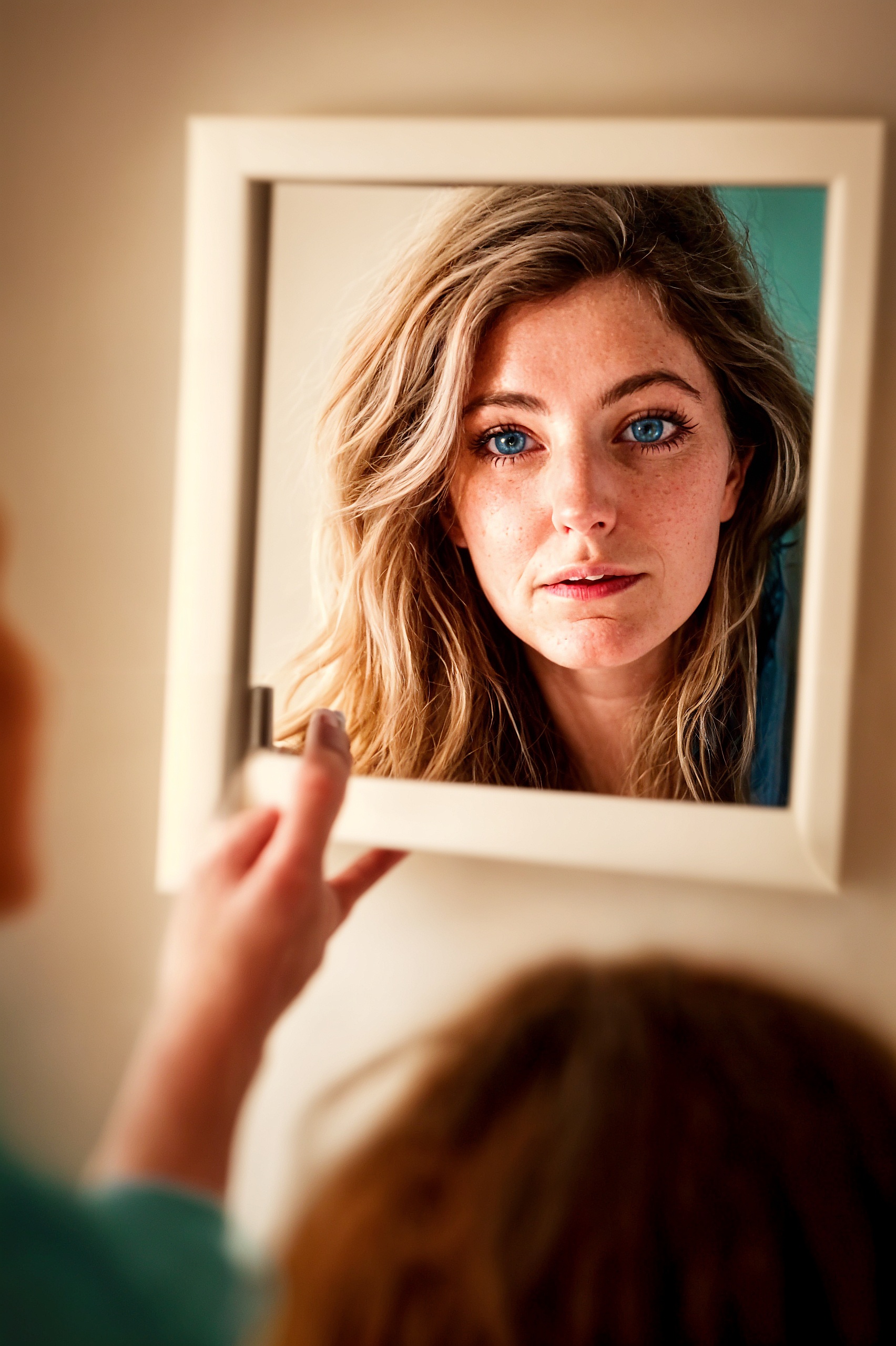 a woman is looking at her reflection in a mirror