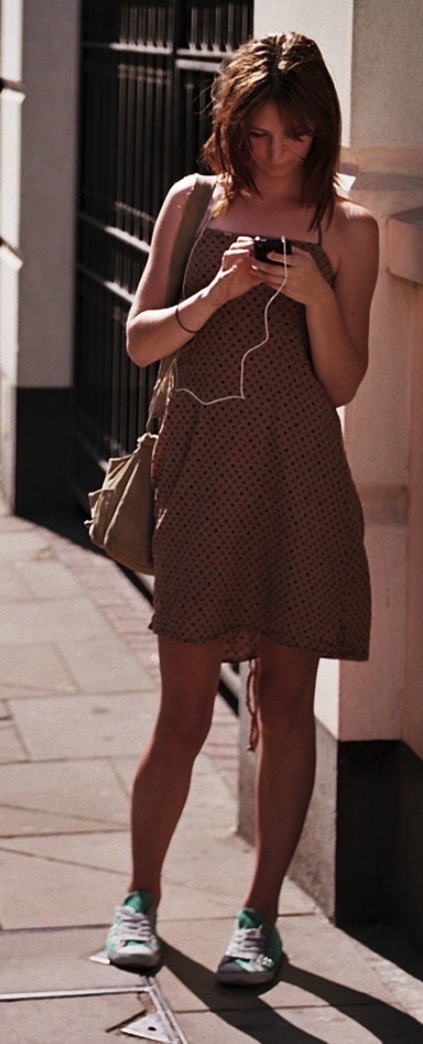 a woman standing on a sidewalk with a cellphone