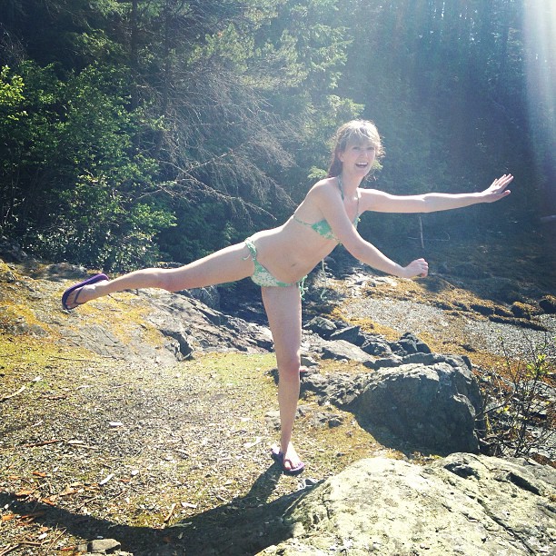 a woman in a bikini is standing on rocks