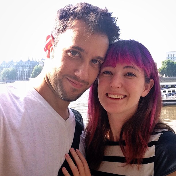 a man and woman posing for a photo in front of a river