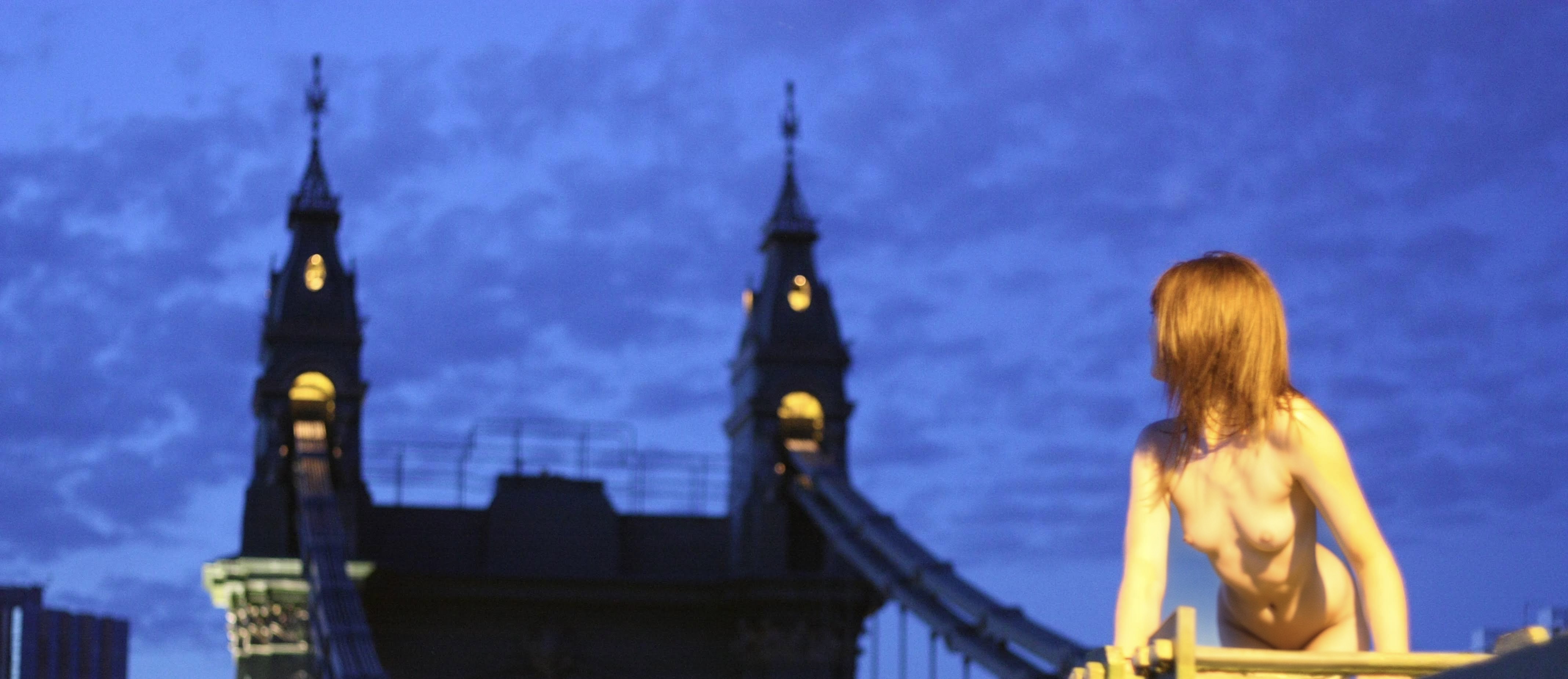 a woman sitting on a bench in front of a tower = pe