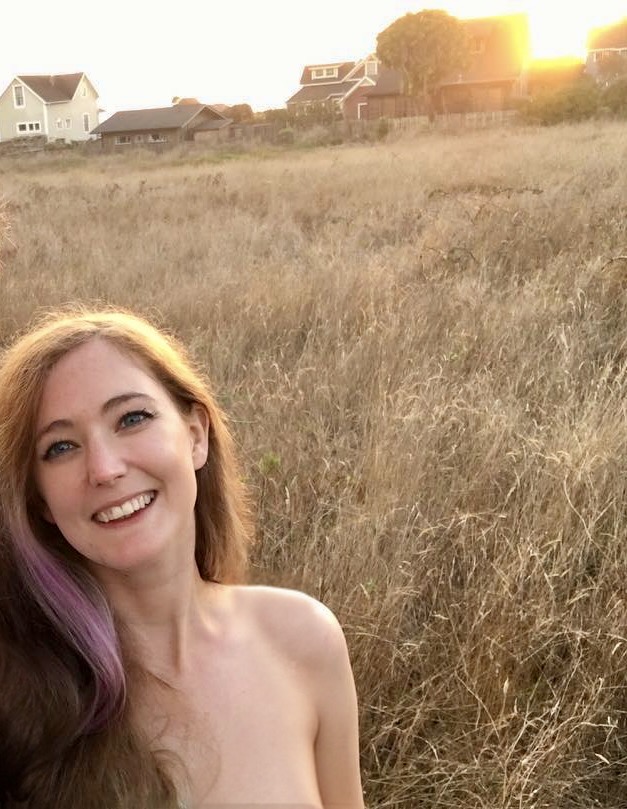 a woman with purple hair and a white shirt is standing in a field