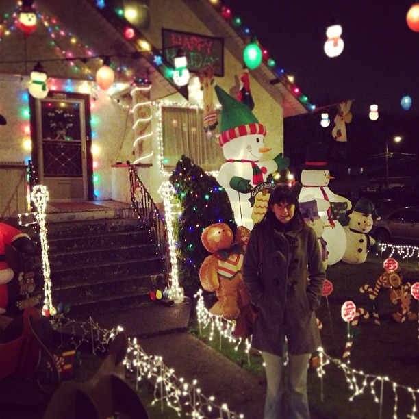 a woman standing in front of a house with christmas lights