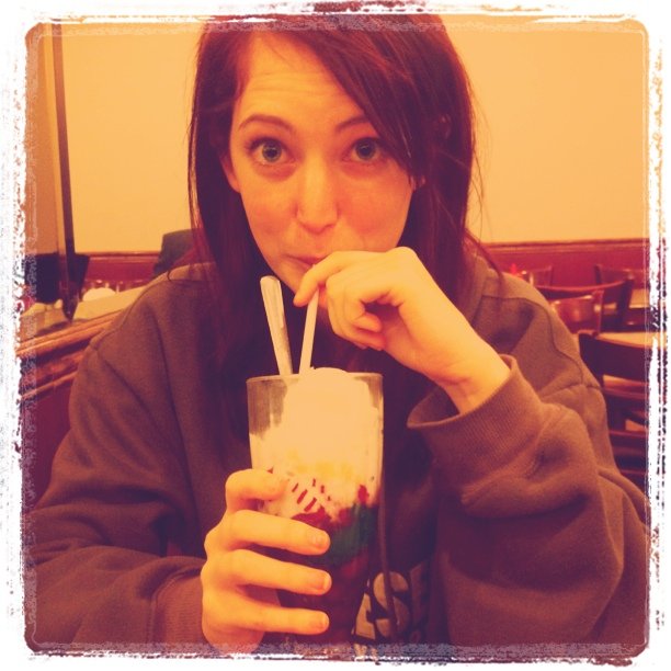 a woman is drinking a drink in a restaurant