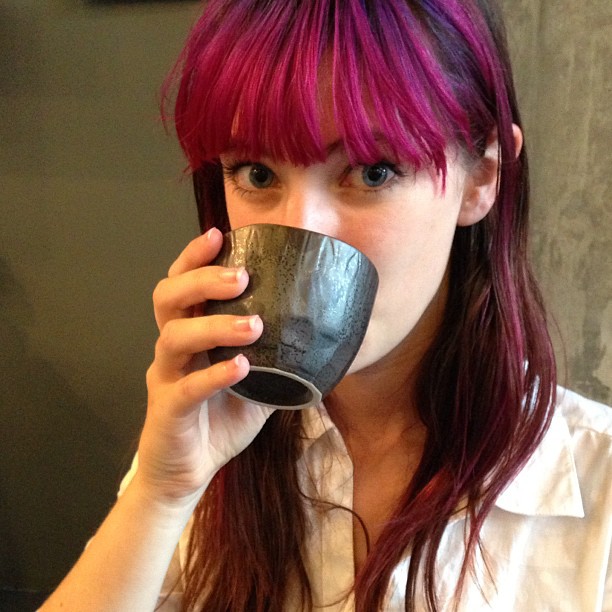 a woman with red hair drinking from a cup