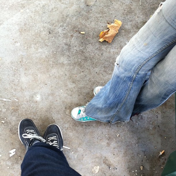 two people standing on the sidewalk with their feet up