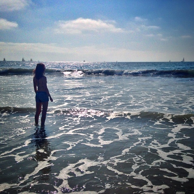 a woman standing in the ocean with her back to the camera