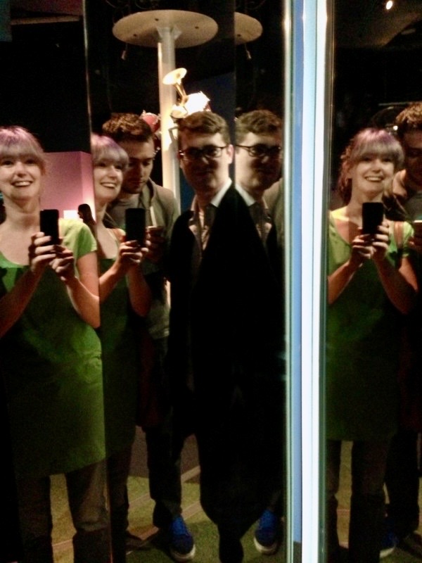 a group of people standing in front of a mirror