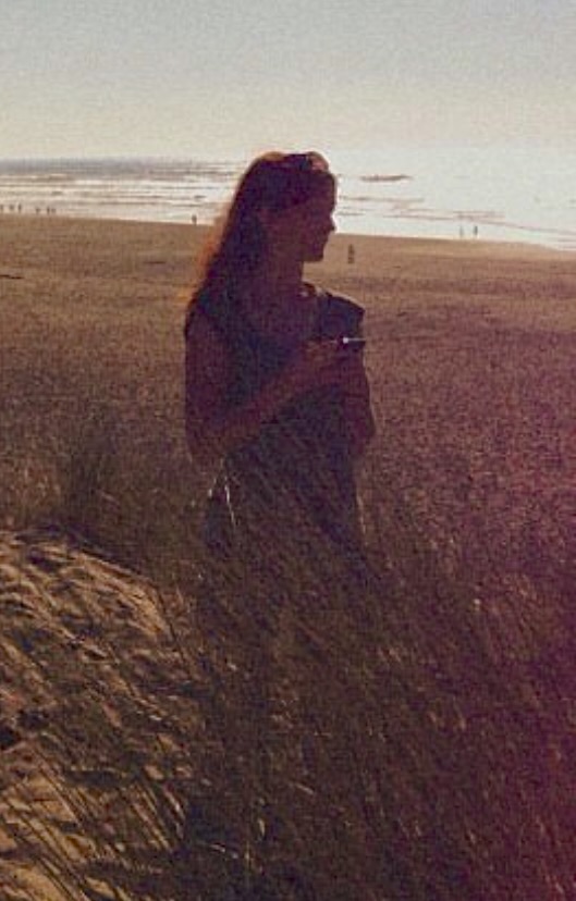 a woman standing on a beach next to the ocean