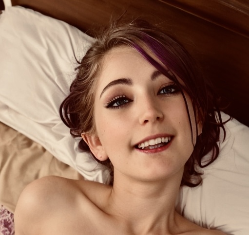 a woman laying in bed with purple hair