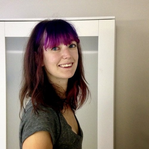 a woman with purple hair standing in front of a mirror