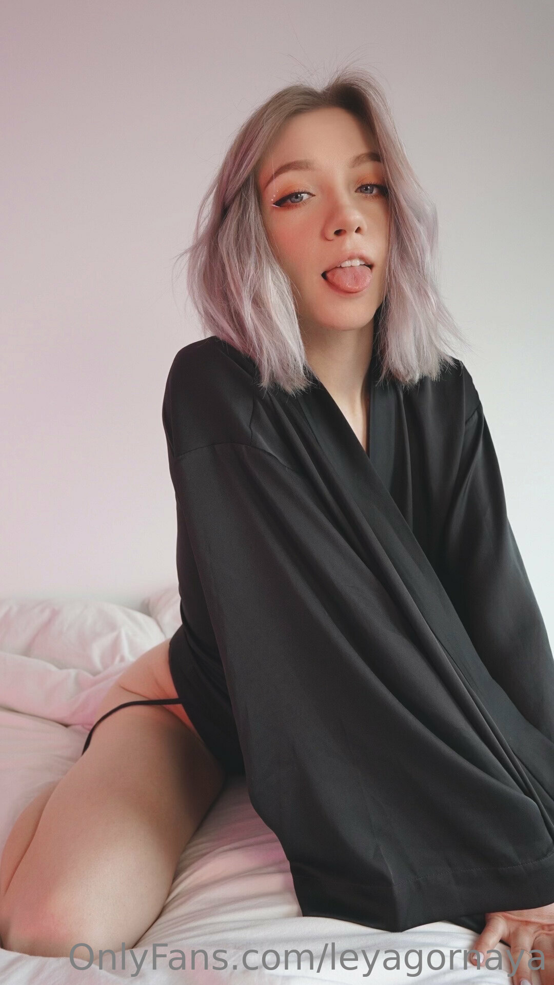 a woman with pink hair sitting on a bed