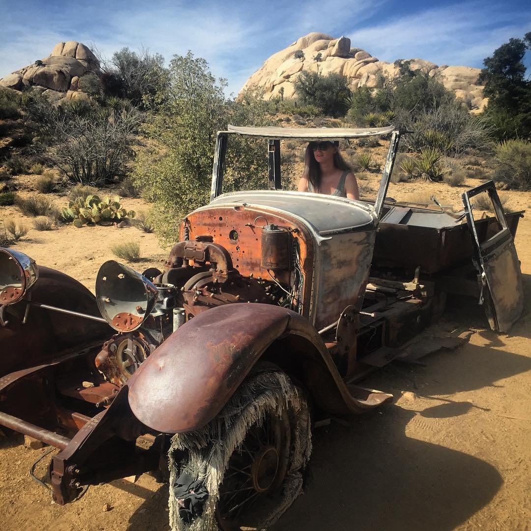 a rusted old car in the desert