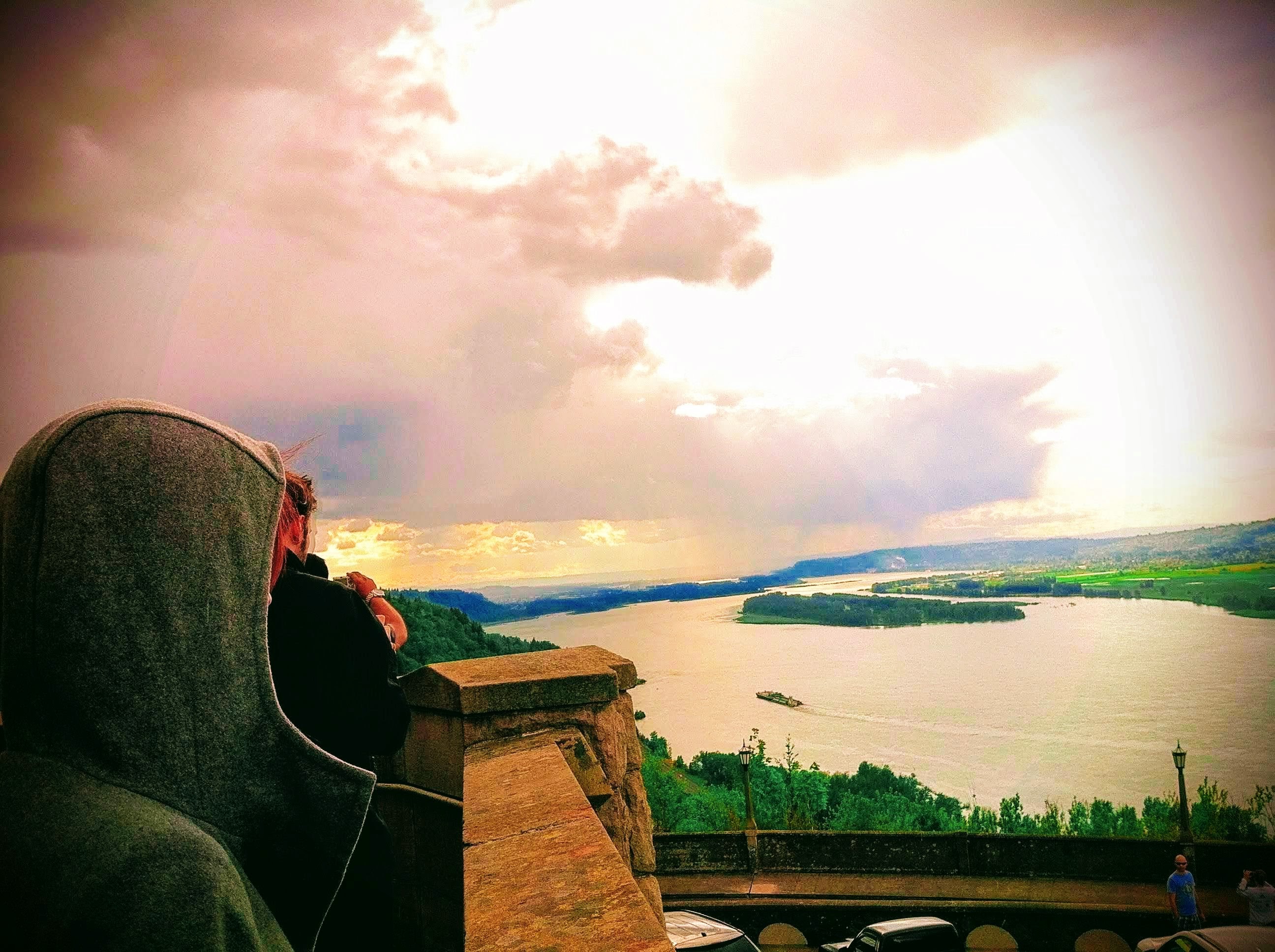 a person sitting on a ledge overlooking a lake