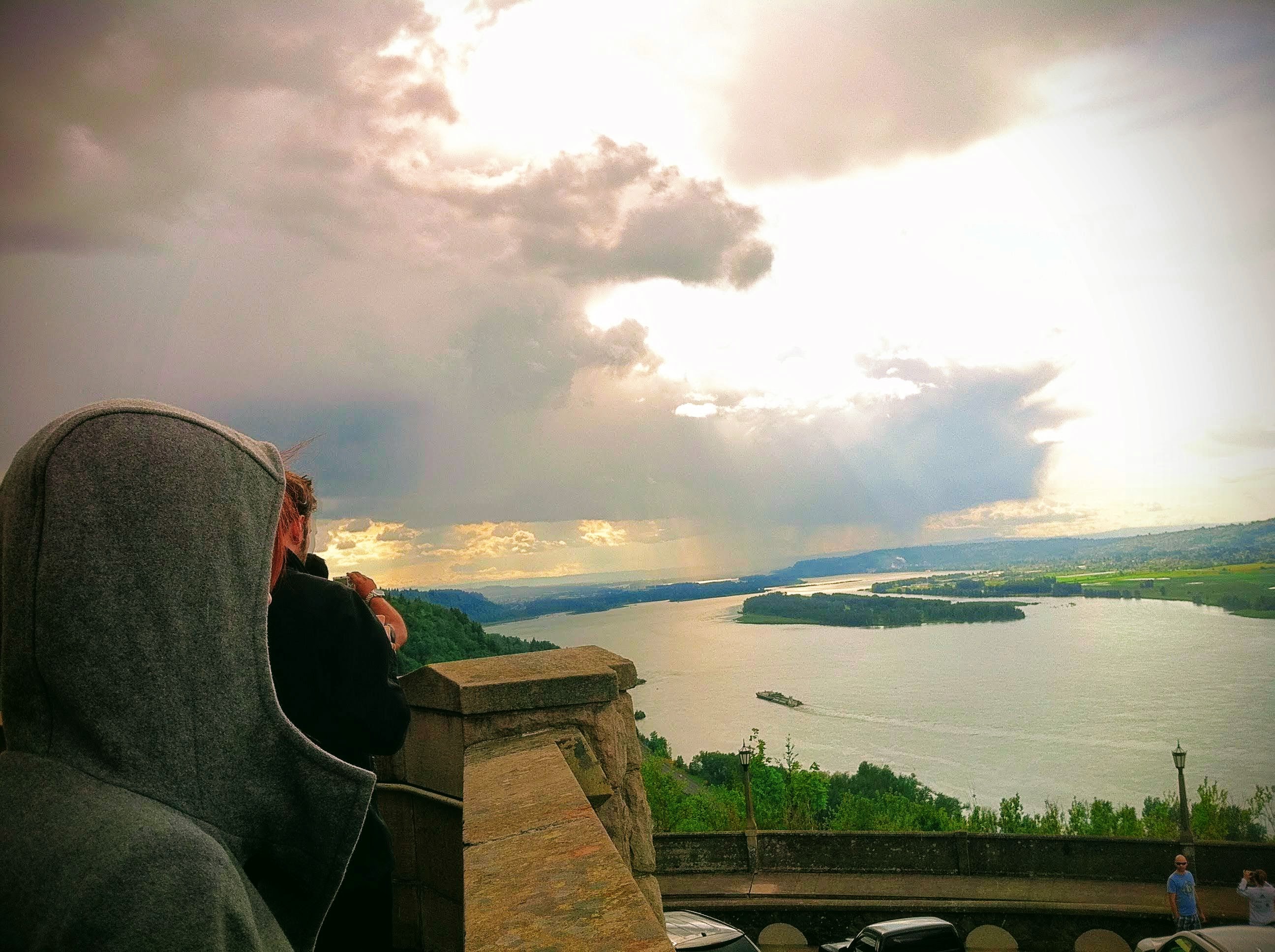 a person sitting on a ledge overlooking a lake