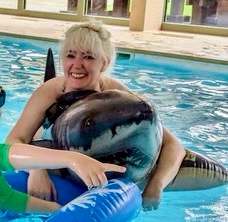 two people in a pool with dolphins