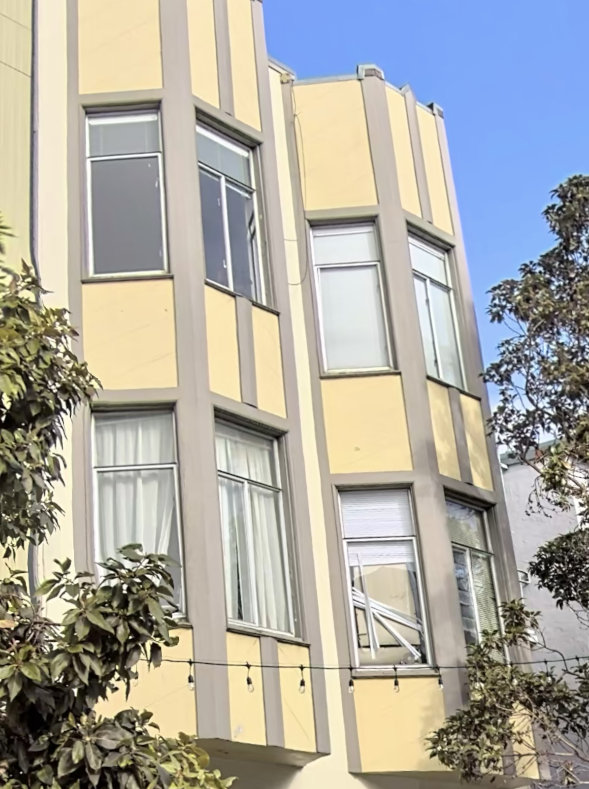 a yellow building with many windows and trees