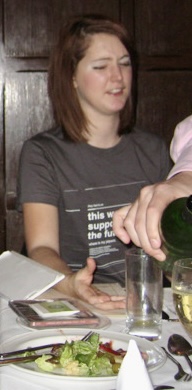 a woman pouring a glass of wine at a table