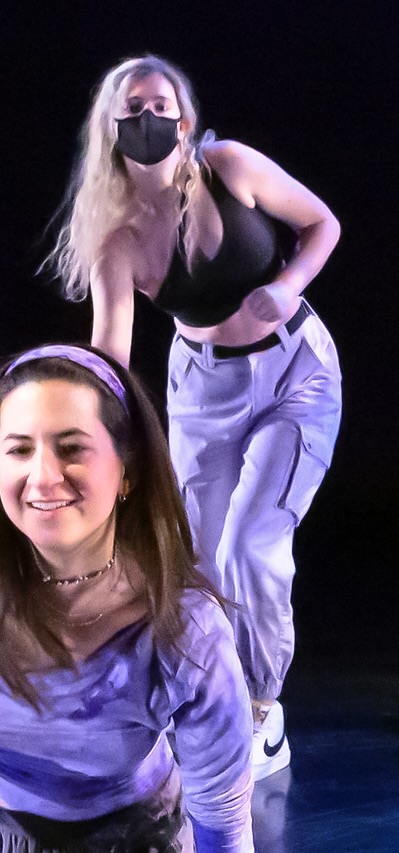 two women in purple outfits are dancing on a stage