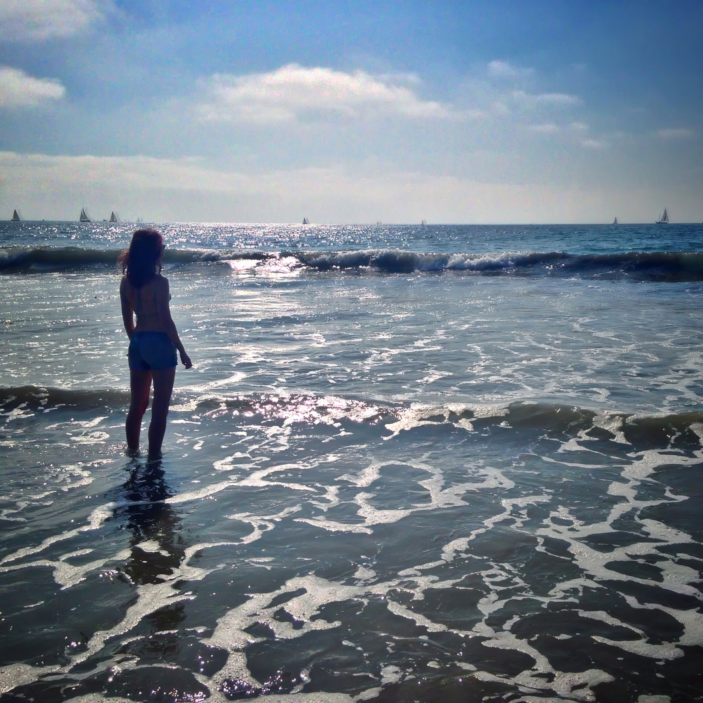 a woman standing in the ocean with a surfboard