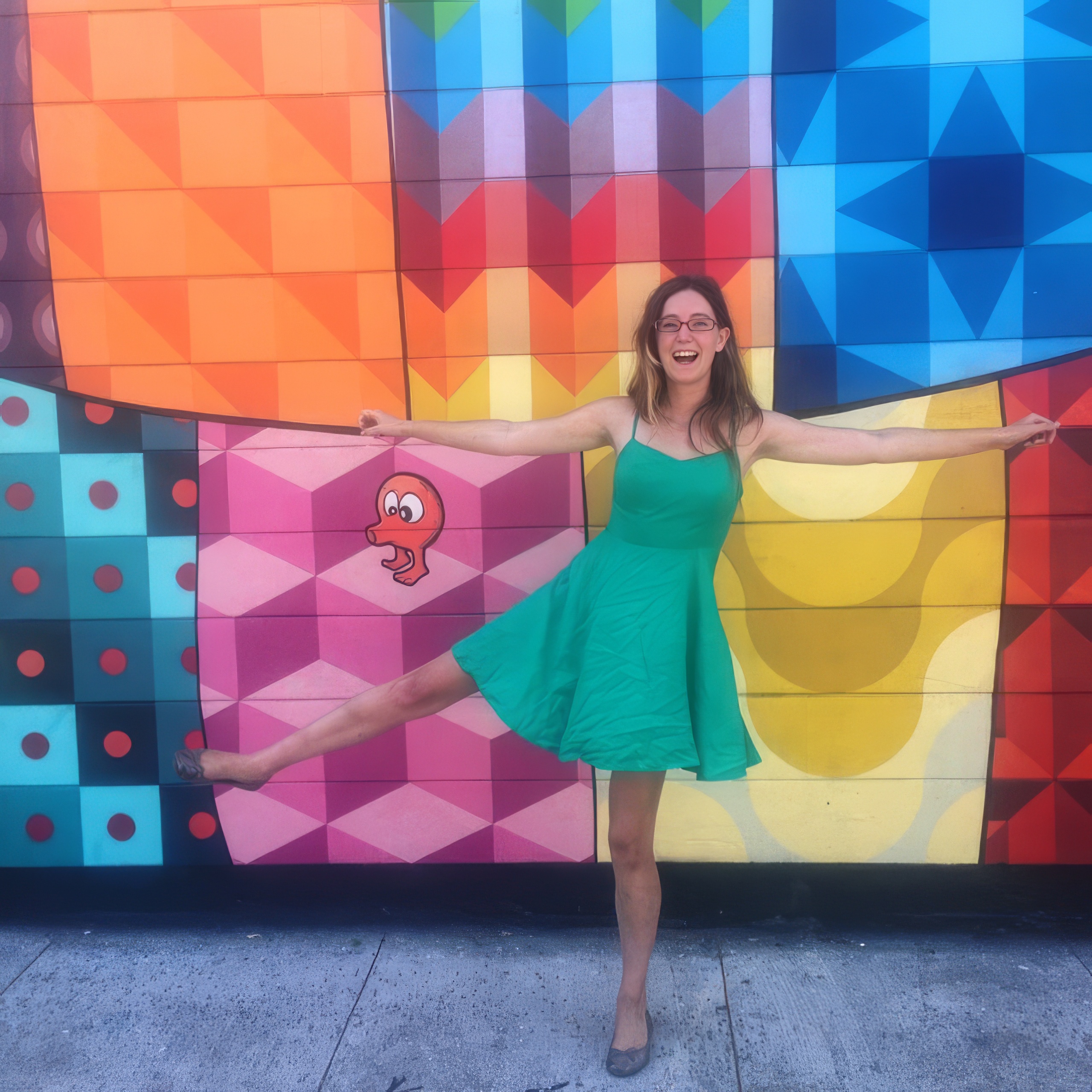 a woman in a green dress is posing in front of a colorful wall