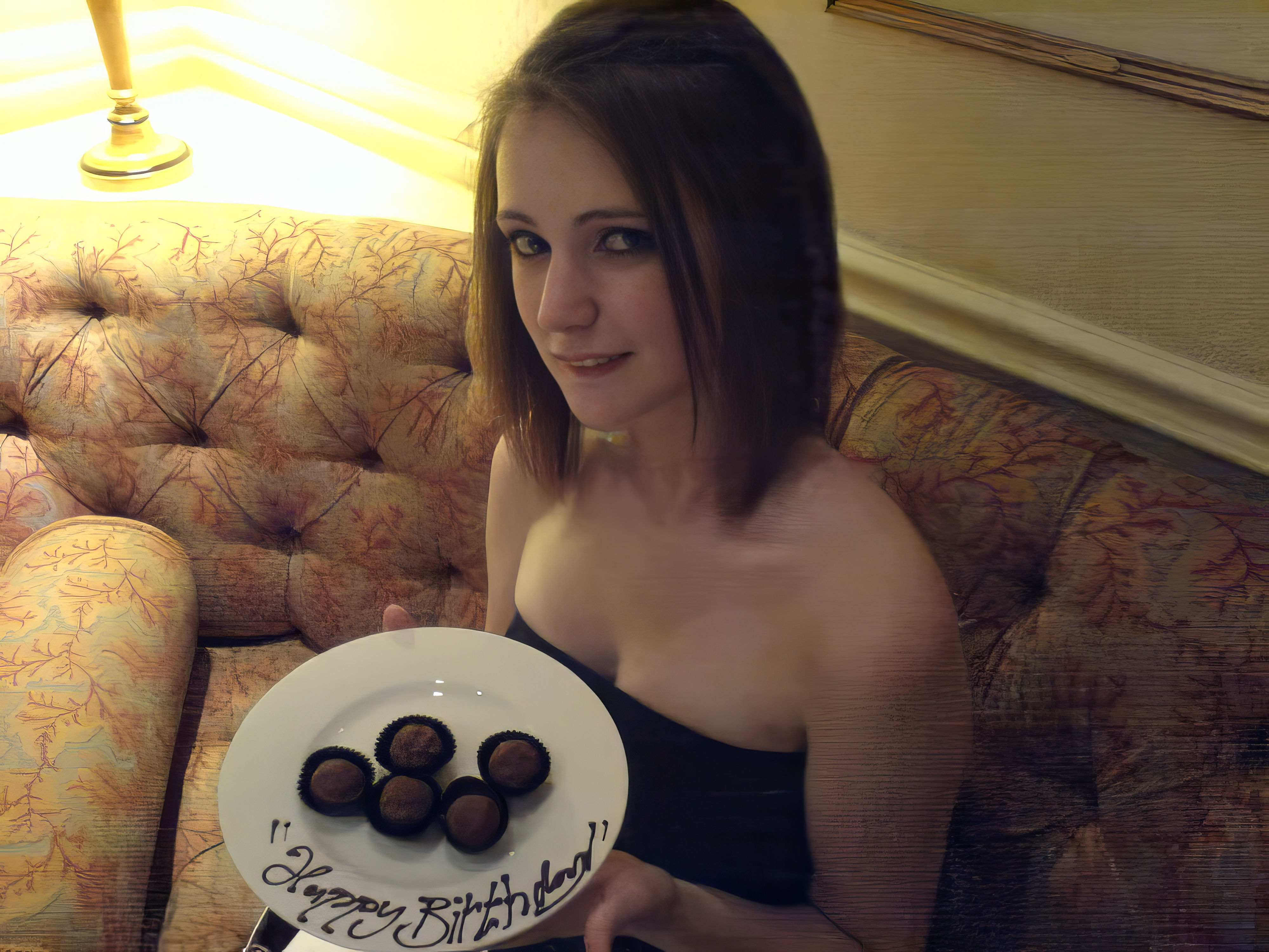 a woman sitting on a couch holding a plate of chocolate covered dons