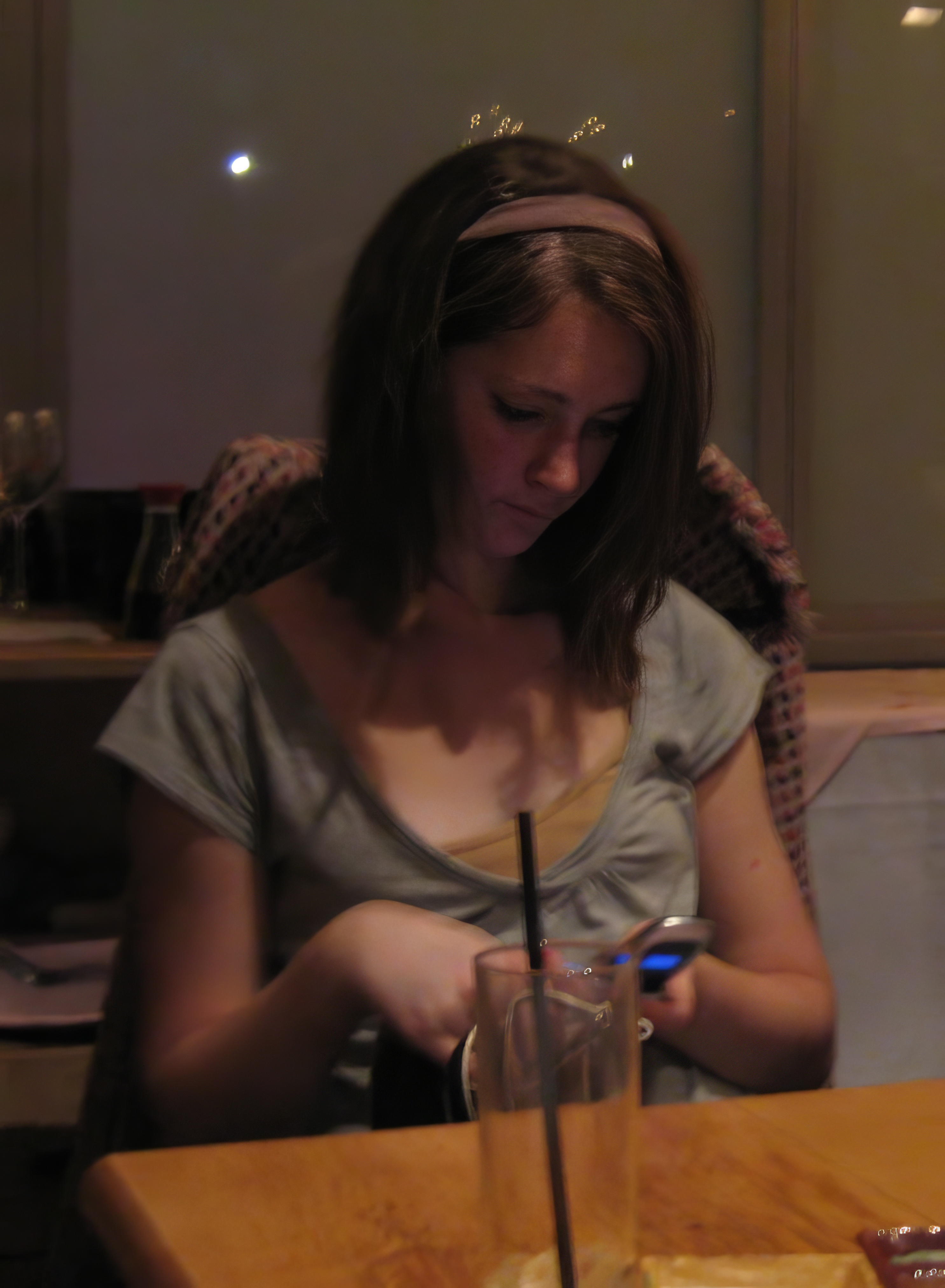 a woman sitting at a table with a cellphone a ae