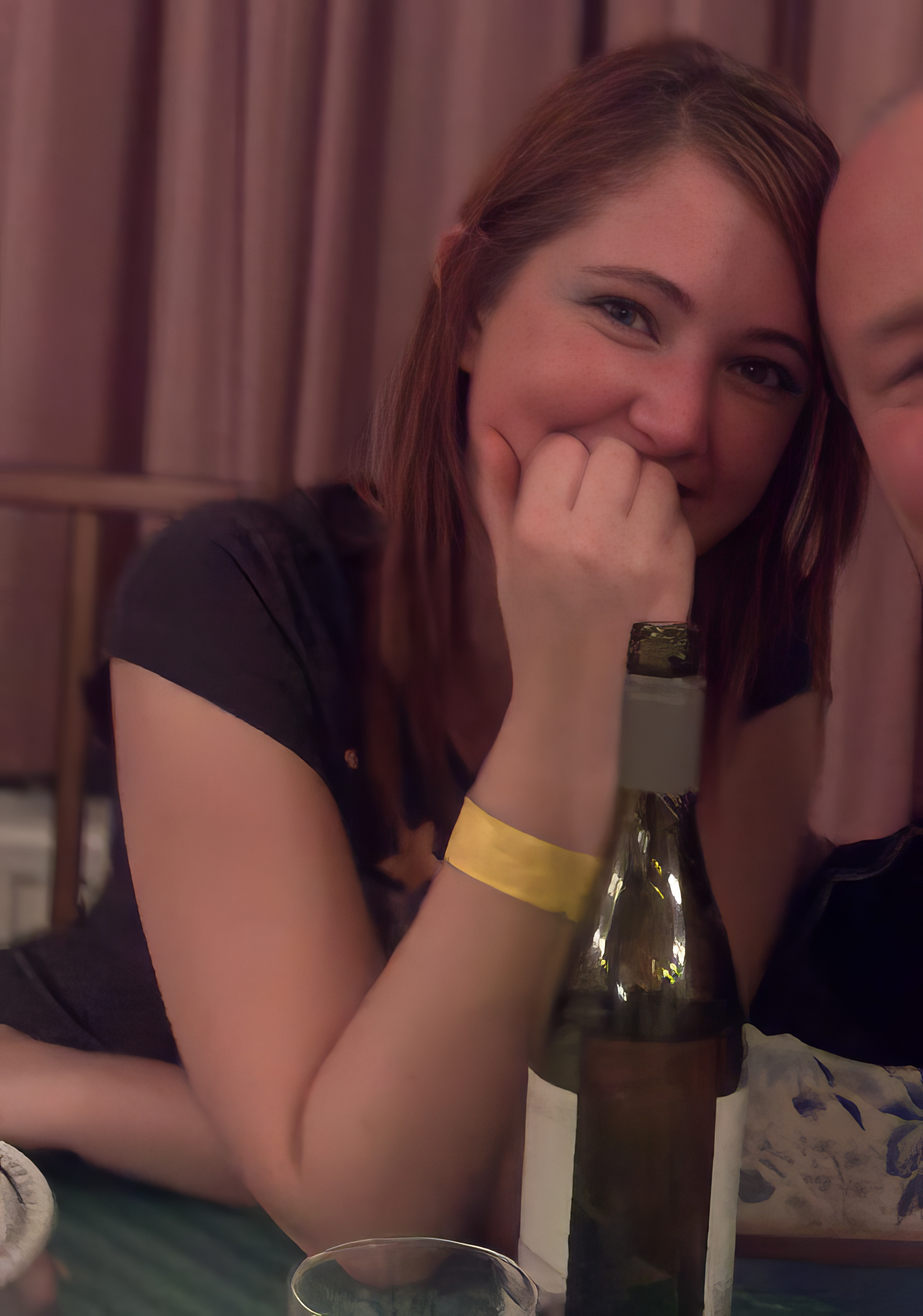 a man and woman sitting at a table with a bottle of wine