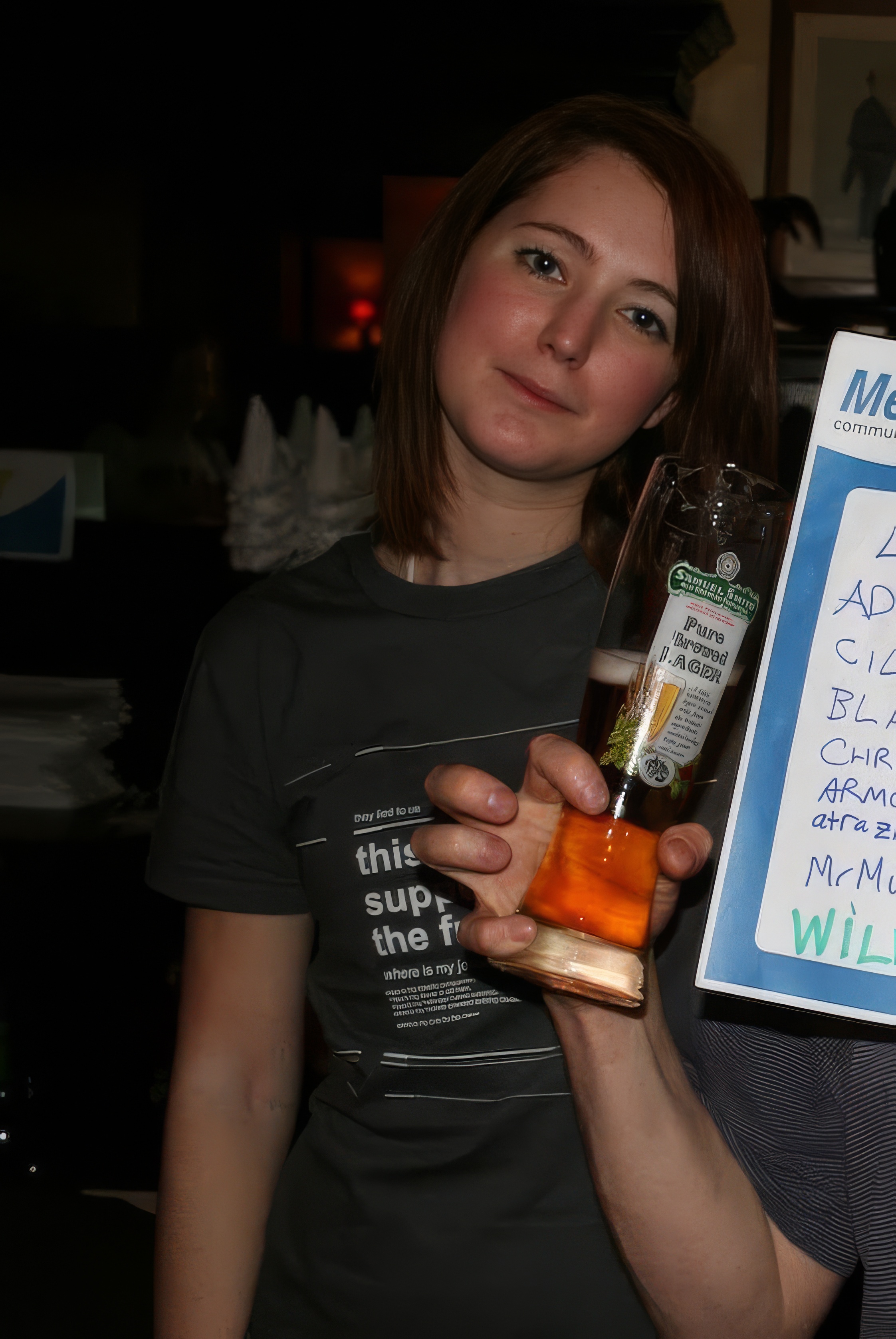 a woman holding a sign with a bottle of alcohol