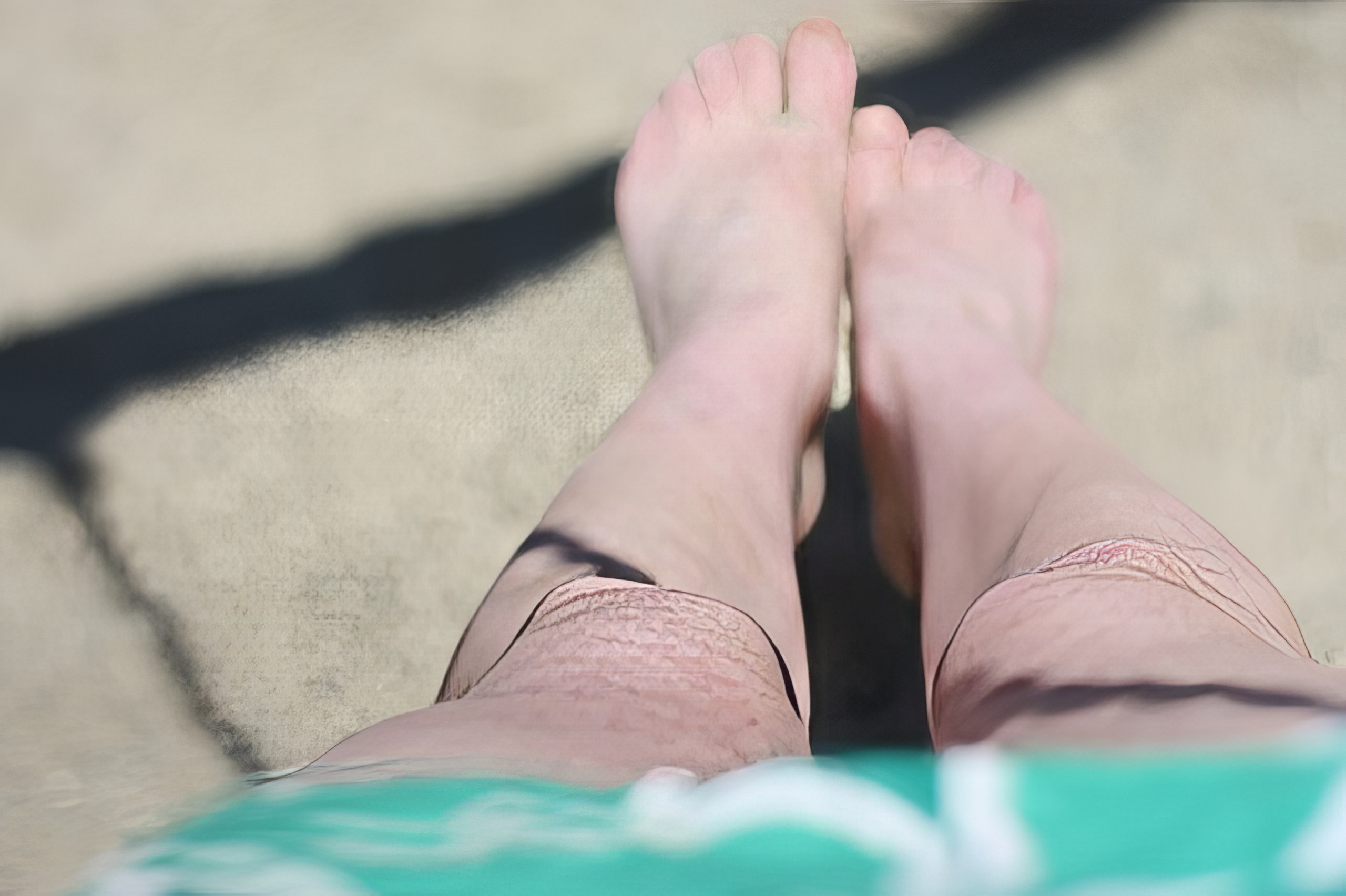 a person's feet are visible on a beach towel