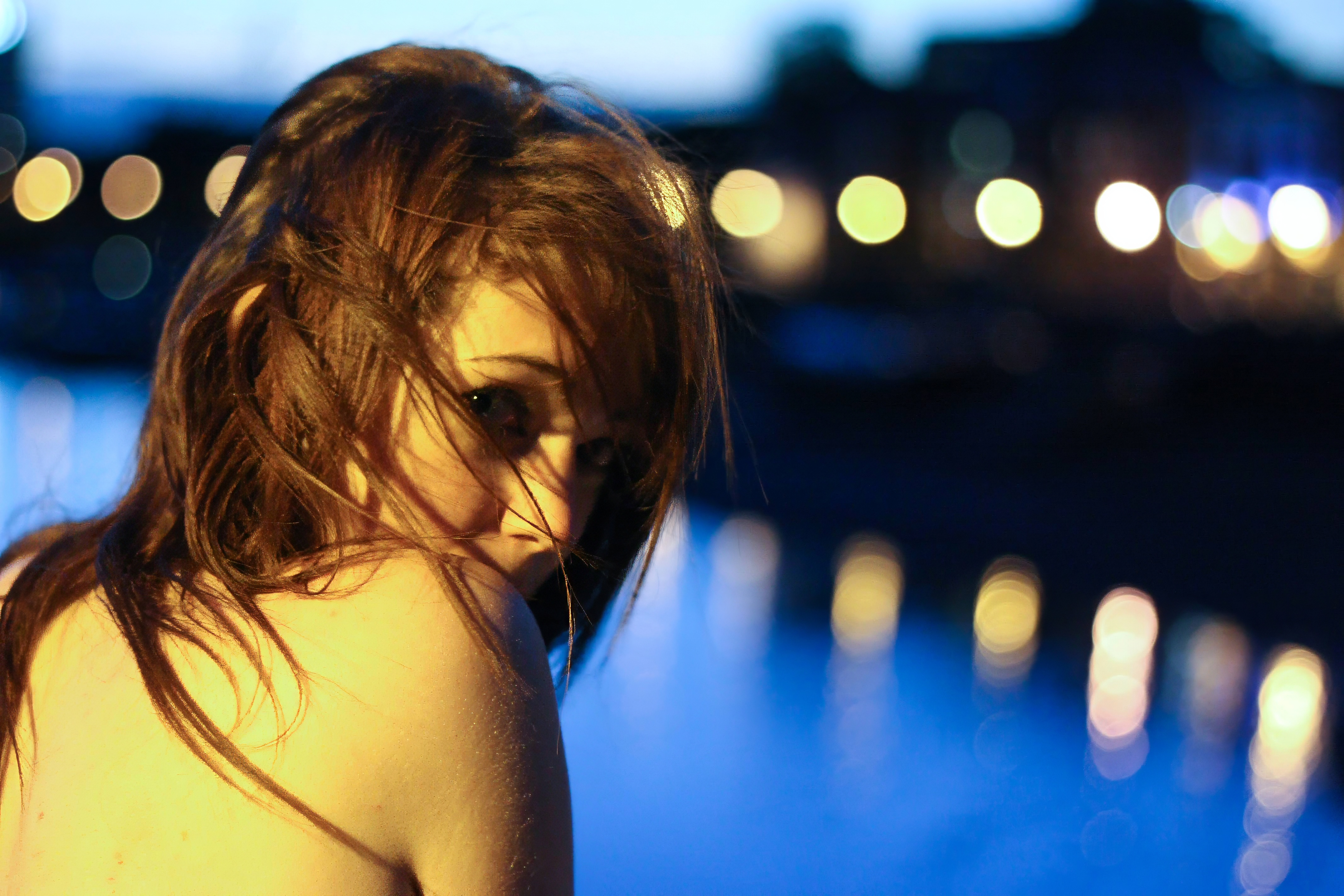 a woman with long hair standing in front of a body of water